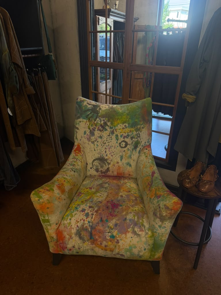 A paint splattered chair by the window